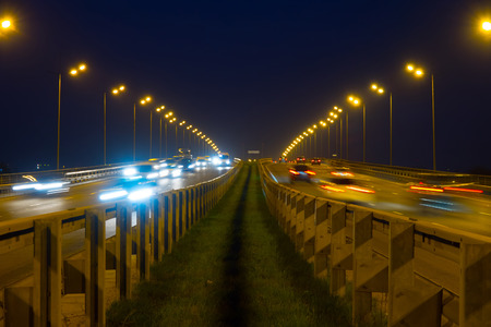Highway traffic cars at night blured. Cars moving on road on bridge evening blurry.の写真素材