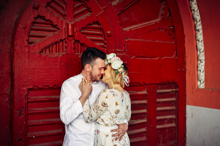 Portrait of two loving people standing isolated on red background, woman wants to kiss her husbandの写真素材