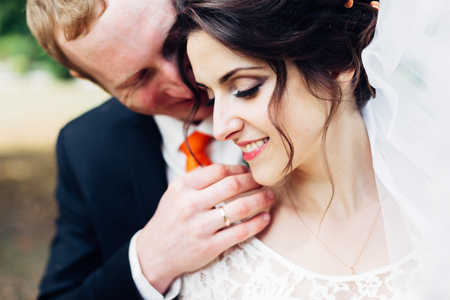 Portrait of a beautiful wedding couple. Groom caresses his bride.の写真素材