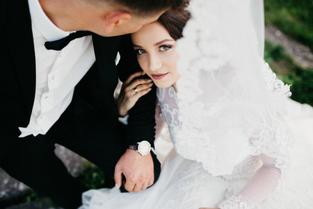 Sensual portrait of a wedding couple. Bride is sitting nearby her groom, holding his hand an looking at the camera.の写真素材