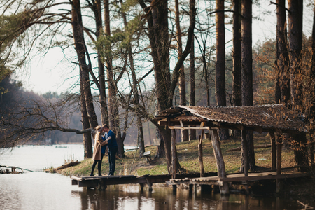 Beautiful portrait of a pregnant woman and her husband. They are walking in the forest, standing near the river, embracing and standing face to face.の写真素材
