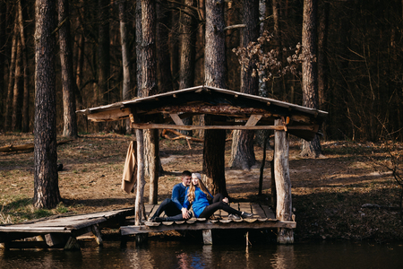 Beautiful portrait of a pregnant woman and her husband. They are walking in the forest, sitting near the river, holding their hands.の写真素材