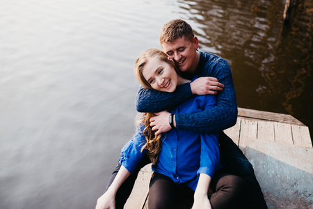 Beautiful portrait of a pregnant woman and her husband. They are walking in the forest, sitting near the river, embracing, looking away and smiling.の写真素材