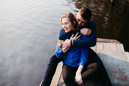 Beautiful portrait of a pregnant woman and her husband. They are walking in the forest, sitting near the river, embracing, looking away and smiling.の写真素材