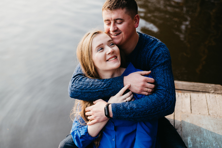 Beautiful portrait of a pregnant woman and her husband. They are walking in the forest, sitting near the river, embracing, looking away and smiling.の写真素材