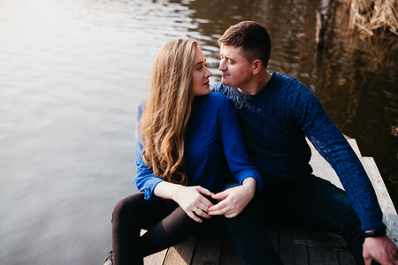 Beautiful portrait of a pregnant woman and her husband. They are walking in the forest, sitting near the river, embracing, looking at each other.の写真素材
