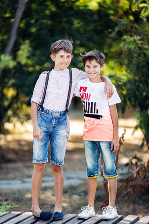 Portrait of a two little brothers. They are standing on the bench, embracing and smiling.の写真素材