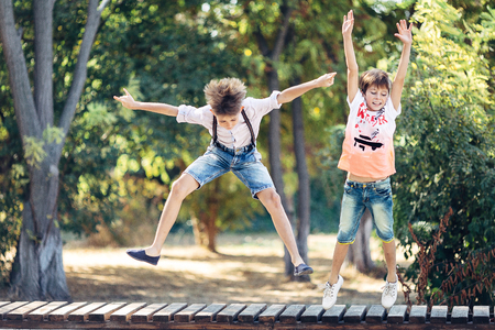 Portrait of a two little brothers. They are jumping on the bench.の写真素材