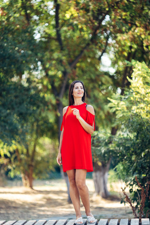 Portrait of a beautiful lady. She is standing on the bench, smiling and looking away.の写真素材