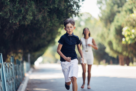 Portrait of a young happy mother and her little son. They are walking in the park, runninng and smiling.の写真素材