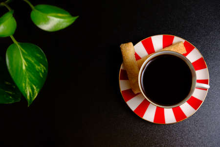 Coffee in a cup, cookies and black backgroundの写真素材