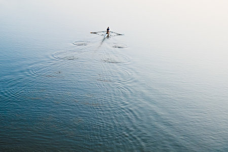 A man is sailing on a boat on the river.の写真素材
