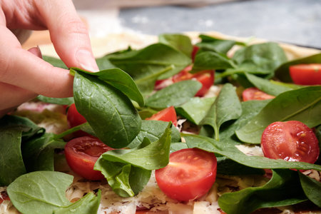 Pizza with cheese, tomatoes, spinach and smoked sausageの写真素材