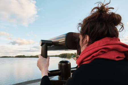 A young girl looks through a large city binoculars. City landmarksの写真素材