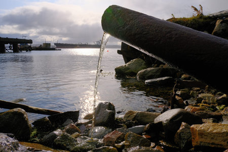 Water pours from a rusty pipe to the coastal part. Environmental protection, pollution of the worlds...