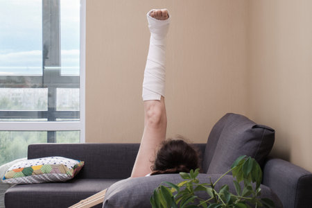 A woman with a cast on her leg is doing physical exercises. Rehabilitation after injury.