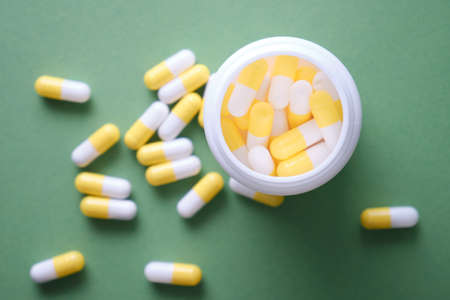 The pills are scattered on the table. Tablets on the green background. Medicinal tablets, capsules, pills.の写真素材