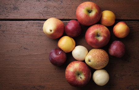 Juicy fruits on a old wooden table. Apples, pears, plums, apricots on a dark red background. Top...