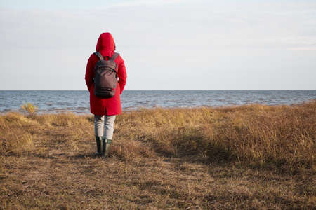 A Woman in a Red Jacket Looks at the Foamy Wavesの写真素材
