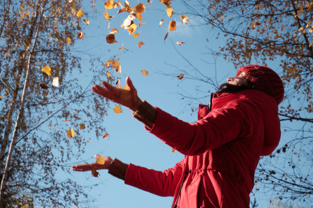 A Woman in A Red Jacket Throws Yellow Leaves. Autumn Landscape. Slow motion video.