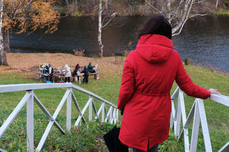 A Woman in a Red Jacket with an Umbrella Walks through the Autumn Park among the Yellow Fallen Leaves.の写真素材