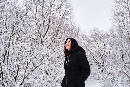 A woman walks alone in a snow-covered park among trees.の写真素材