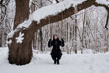 A woman walks alone in a snow-covered park among trees.の写真素材