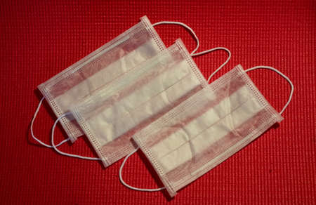 Three white medical protective masks on a red backgroundの写真素材