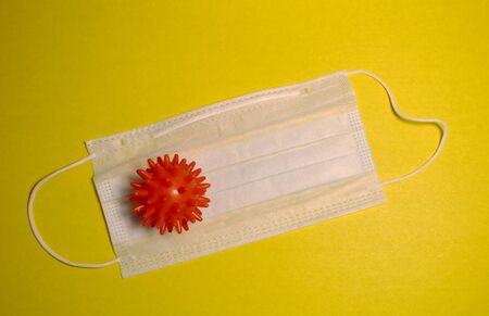 Virus model and medical protective mask on a yellow background.の写真素材