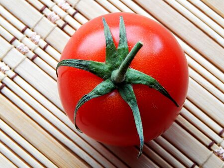 One red tomato on a wooden napkin close up view from aboveの写真素材