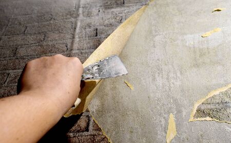 Hand with a spatula, repair and removal of old Wallpaper from the wallの写真素材