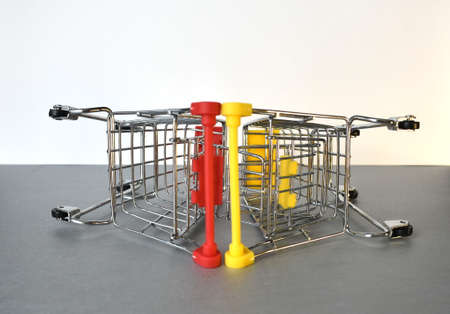 Two empty supermarket carts. They lie on their side, on a gray-white background.の写真素材