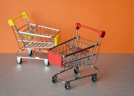Two empty supermarket carts on a gray-orange backgroundの写真素材