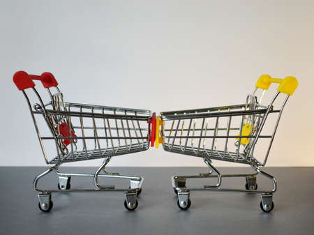 Two empty shopping carts opposite each other on a white-and-gray background.の写真素材
