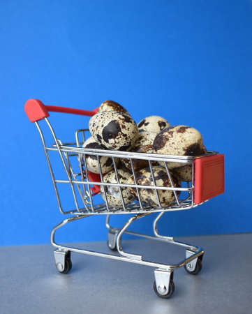 Quail eggs in a grocery basket on a blue-gray backgroundの写真素材
