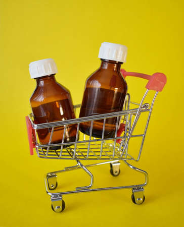 Two brown cosmetic bottles with a white lid in a small grocery cart close-up. The concept of buying cosmetics.の写真素材