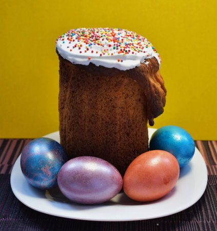 Easter cake and four painted eggs on a white plateの写真素材