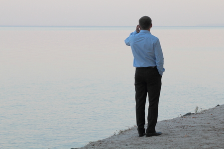 Man talking on the phone near the waterの写真素材