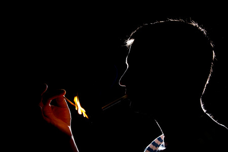 Silhouette of man who lights the cigaretteの写真素材