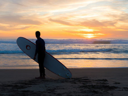 surfer people carrying surfboard on an ocean beach in Portugal