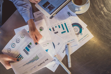 View of business people, sitting at the table and pointing handles on the chart