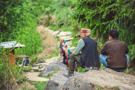 Vashisht. India. April 21, 2017. Local men sit on a rock, surrounded by pines.のeditorial素材