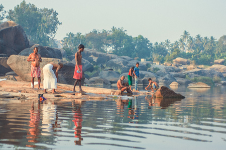 India, Hampi - December 22, 2015: Men wash and wash on the river bank in the morning.のeditorial素材