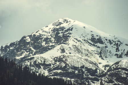 The top of one of the Himalayan mountains with snow in the clouds.