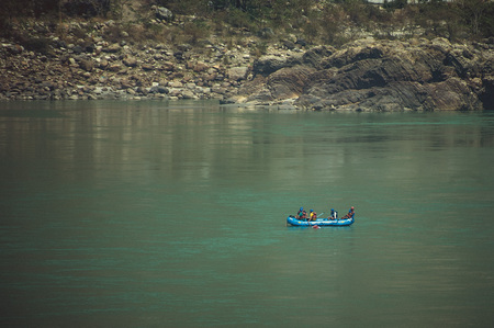 people in a blue boat are rafting on the Ganges Riverの写真素材