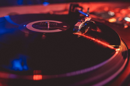 Vinyl record on the turntable in the music club in the light of blue and red light.の写真素材