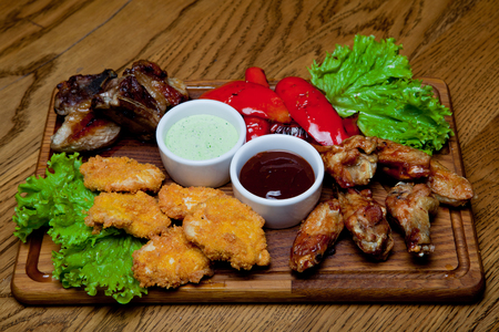 Pork ribs with honey sauce, spicy chicken wings, grilled peppers, chicken nuggets, barbecue sauce, garlic sauceの写真素材