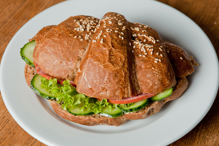 Rye croissant with salami and fresh cucumberRye croissant on a plateの写真素材
