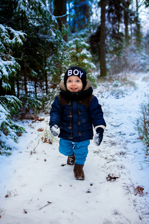 Little boy walking in the winter forestの写真素材
