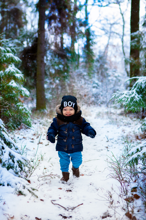 Little boy walking in the winter forestの写真素材
